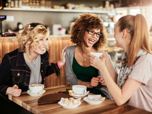 Young women using smart phone Close up of best friends using a mobile phone while at a cafe